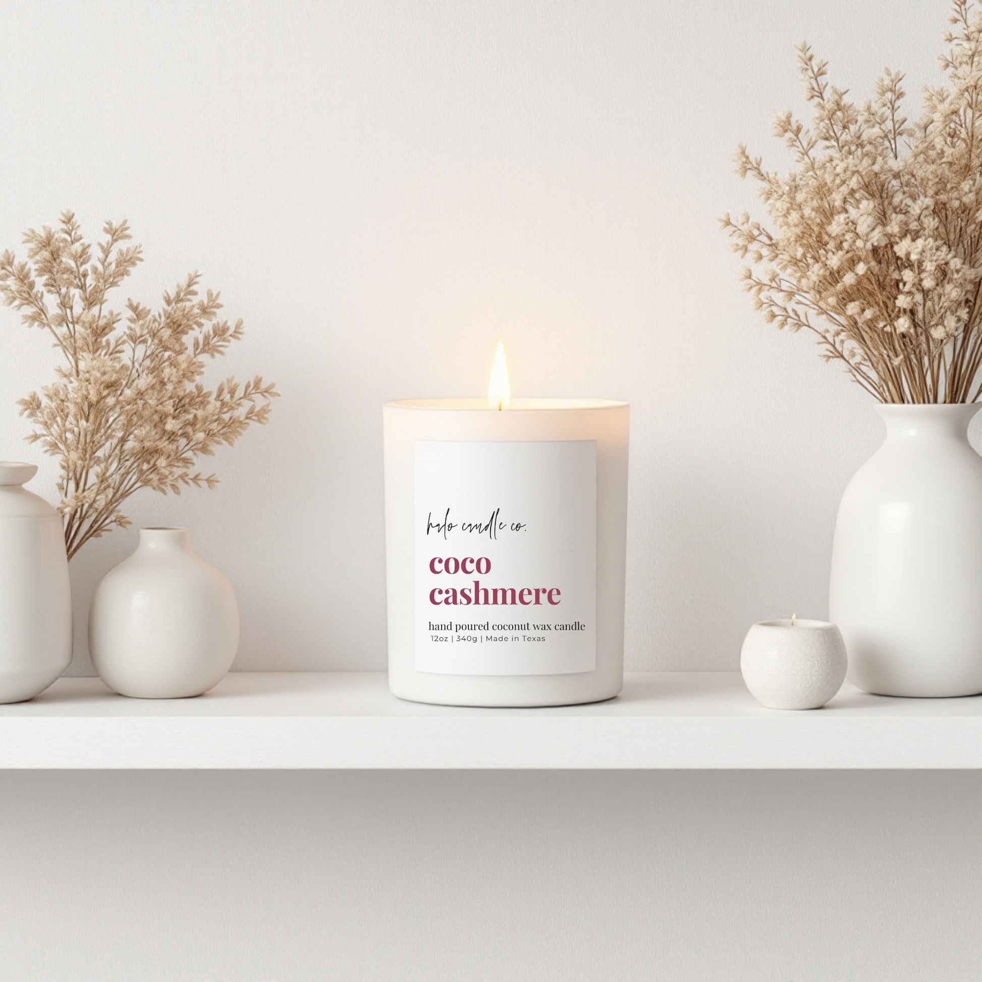 Candle labeled 'coco cashmere' on a shelf with decorative vases and plants.