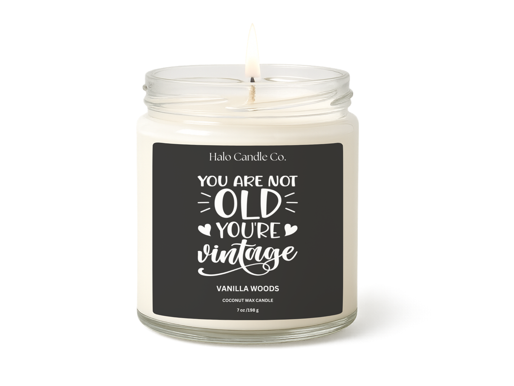 Candle in a jar with a black label featuring text, on a white background